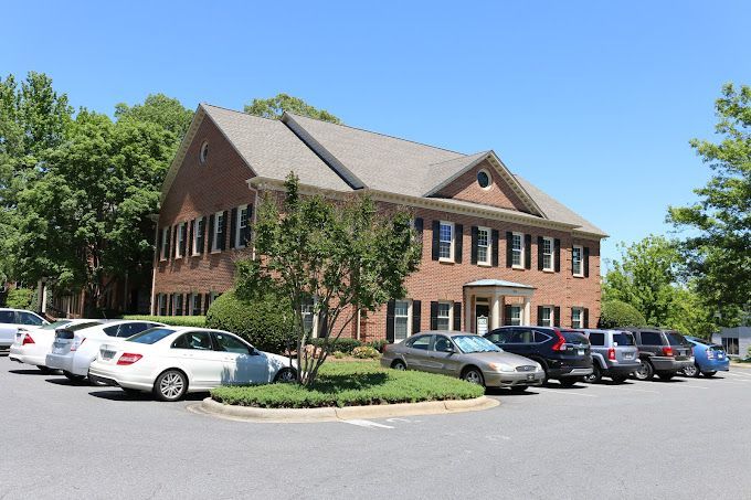 A row of cars are parked in front of a large brick building.