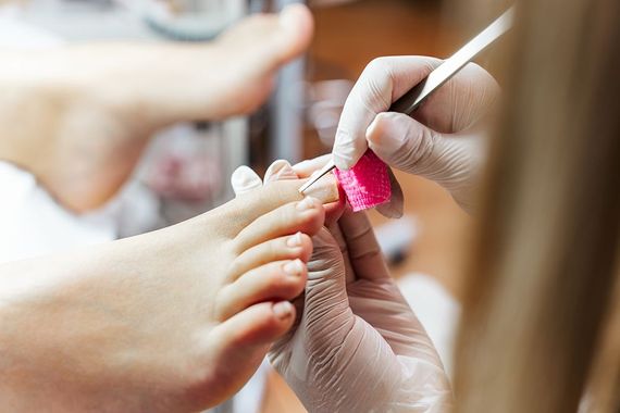 A woman is getting her toenails painted by a nail artist.