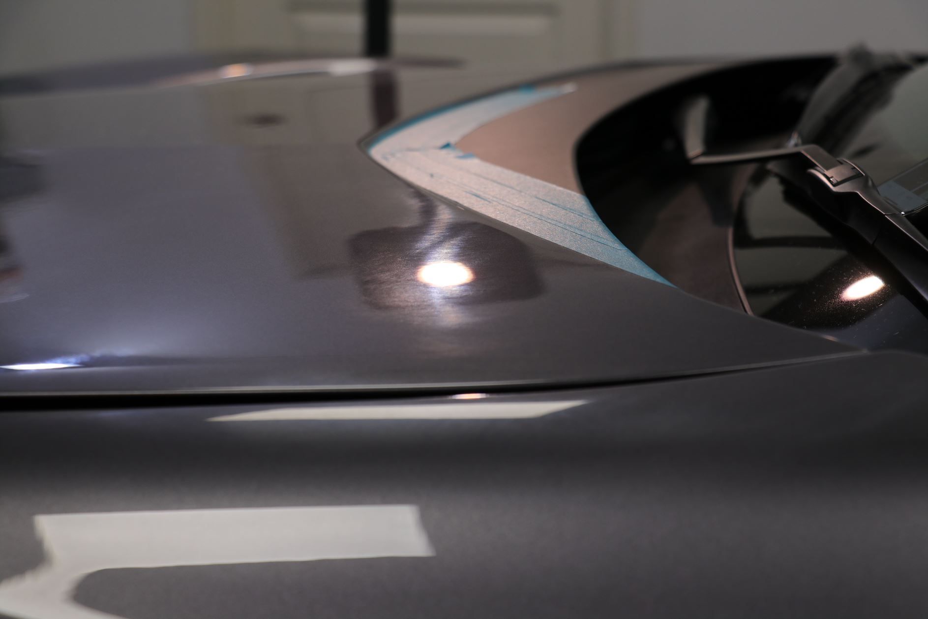 Close-up of a shiny, silver car hood reflecting lights.