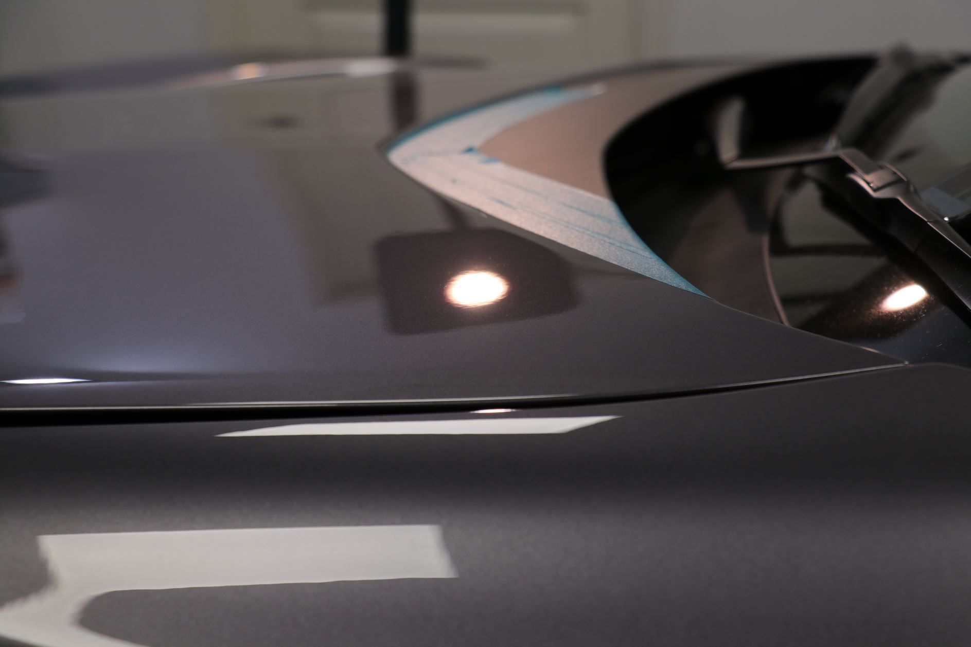 Shiny gray car hood reflecting lights.