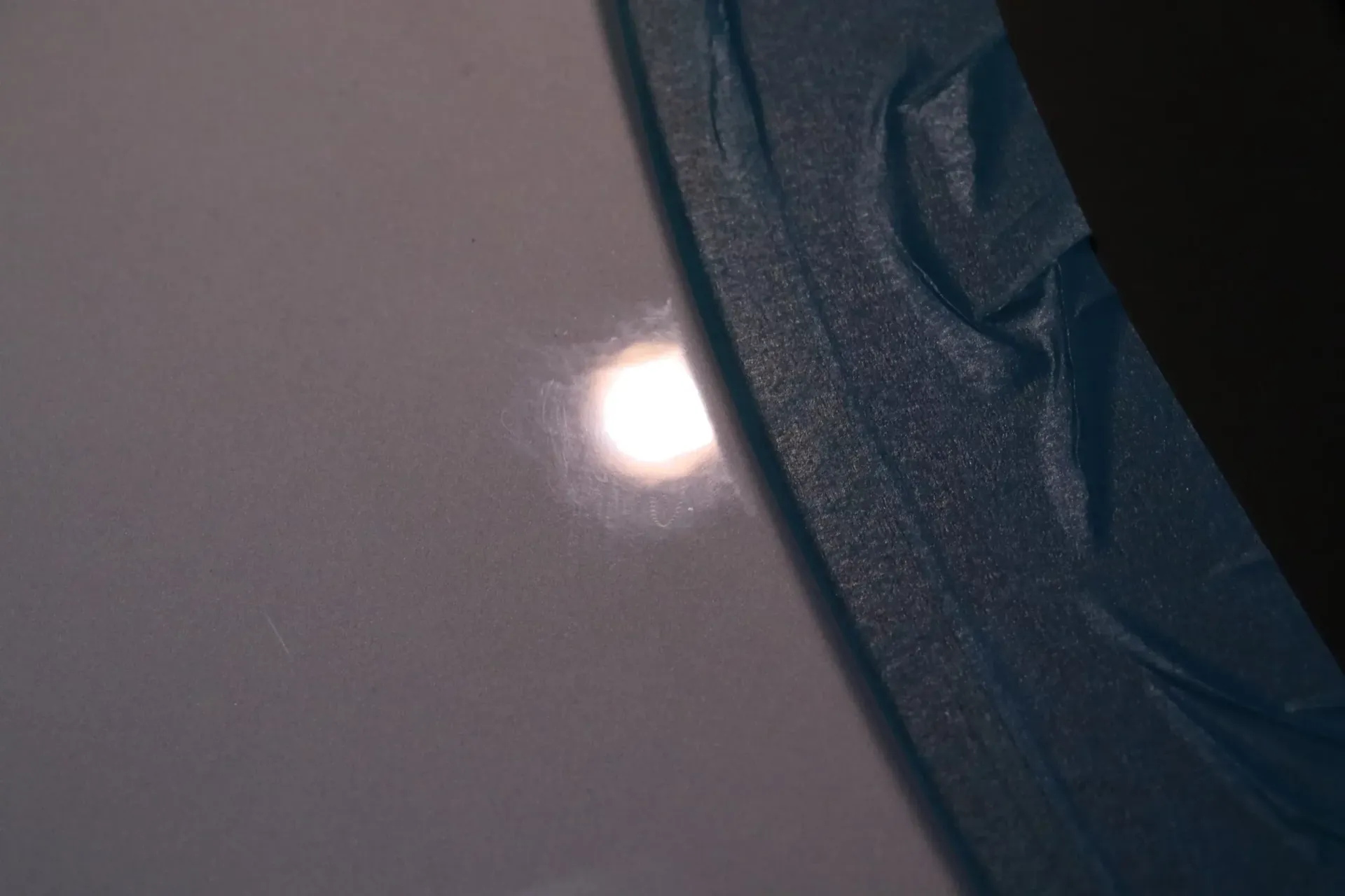 Bright light reflecting off a white surface, partially obscured by blue fabric on the right.
