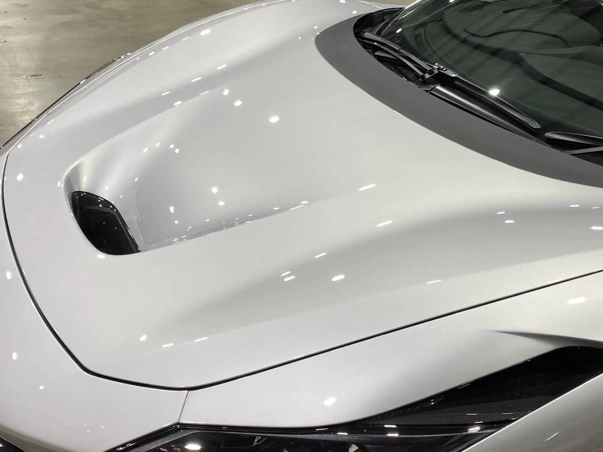 White sports car hood with a central air intake.