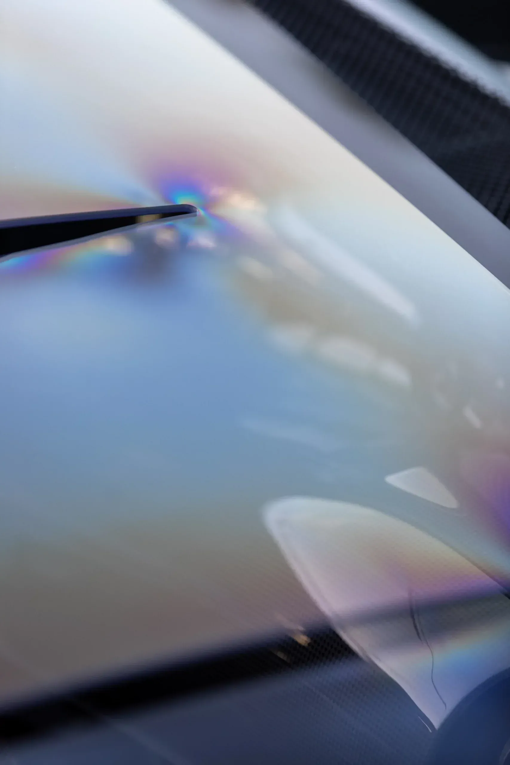 Iridescent oil slick on a reflective surface, with rainbow colors swirling.