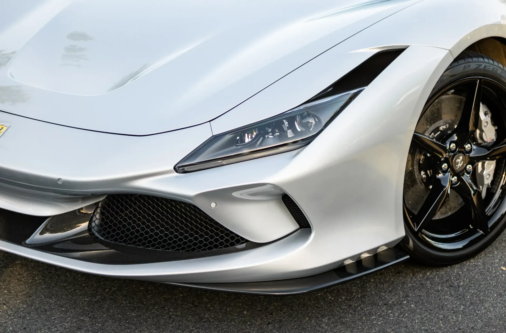 Silver Ferrari sports car, front quarter view, black wheels, headlight detail.