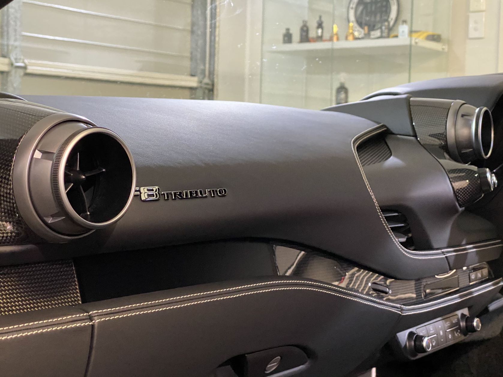Dashboard of a black car, featuring air vents, stitching, and 