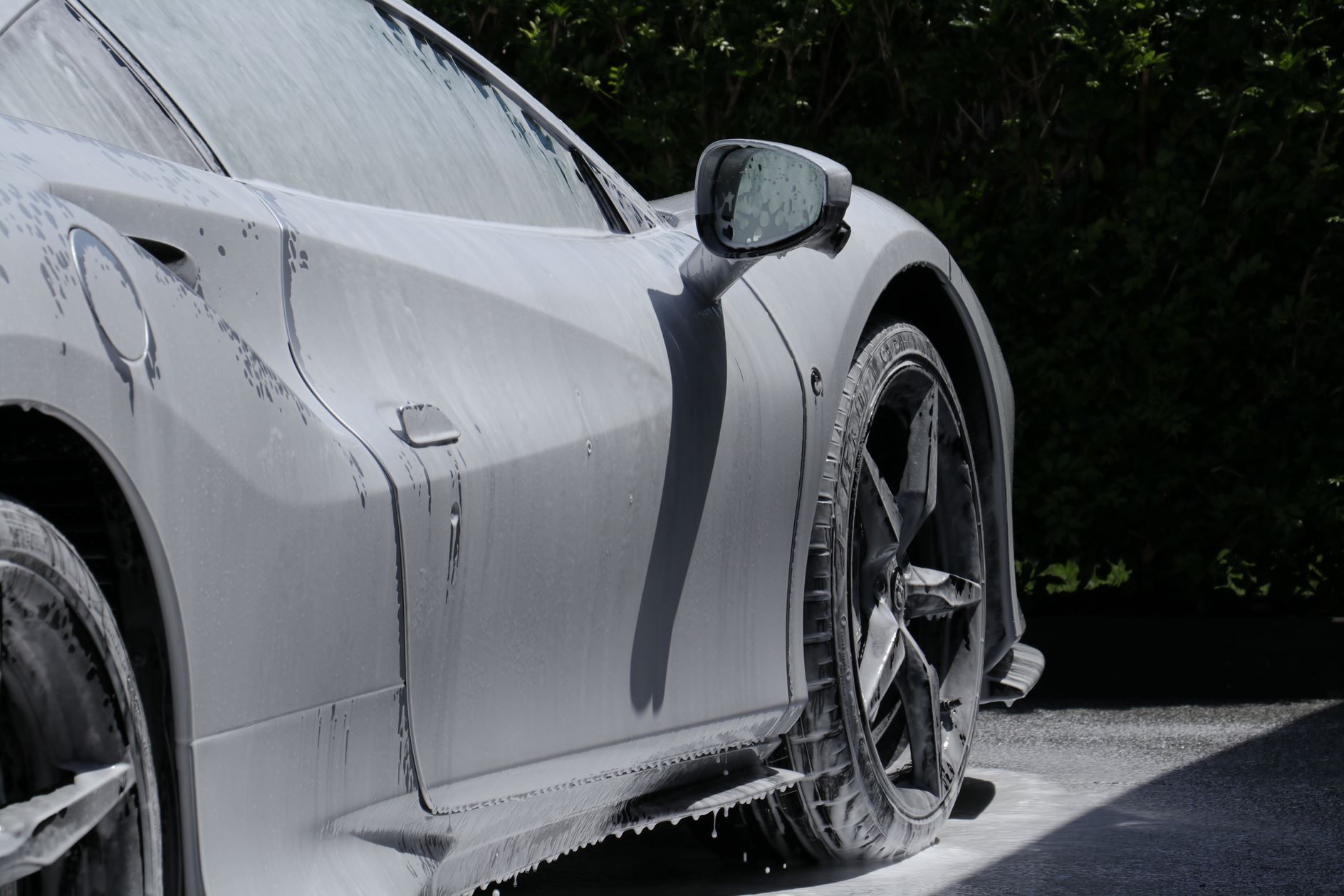 Sports car covered in white foam, undergoing a car wash.