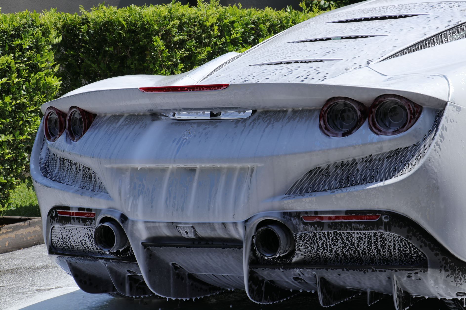 White sports car rear being washed with soap.
