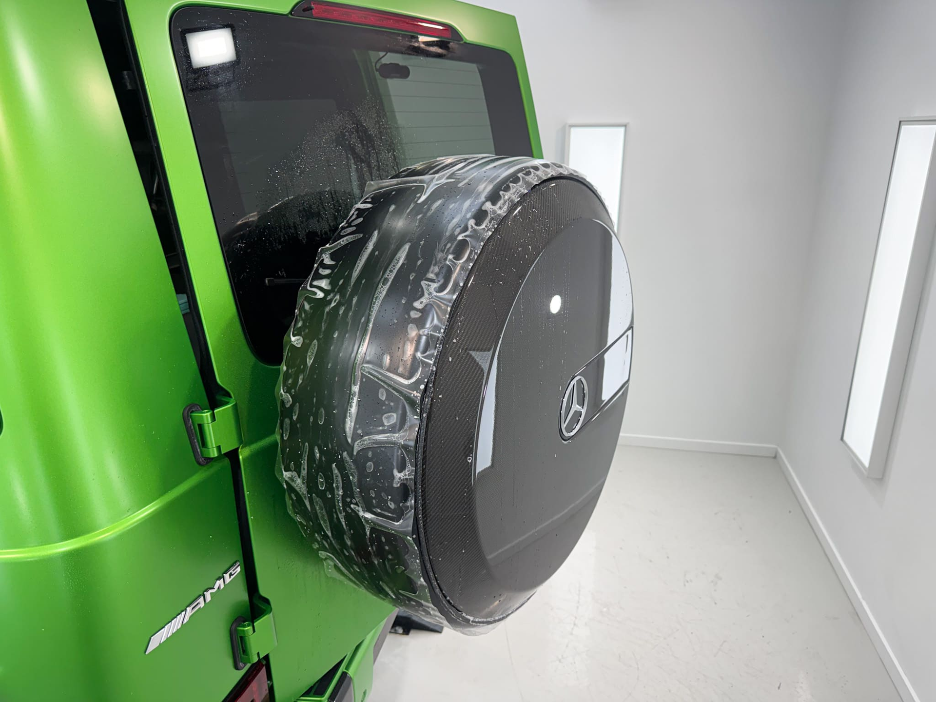 Green Mercedes-Benz G-Class SUV in a brightly lit, white studio.