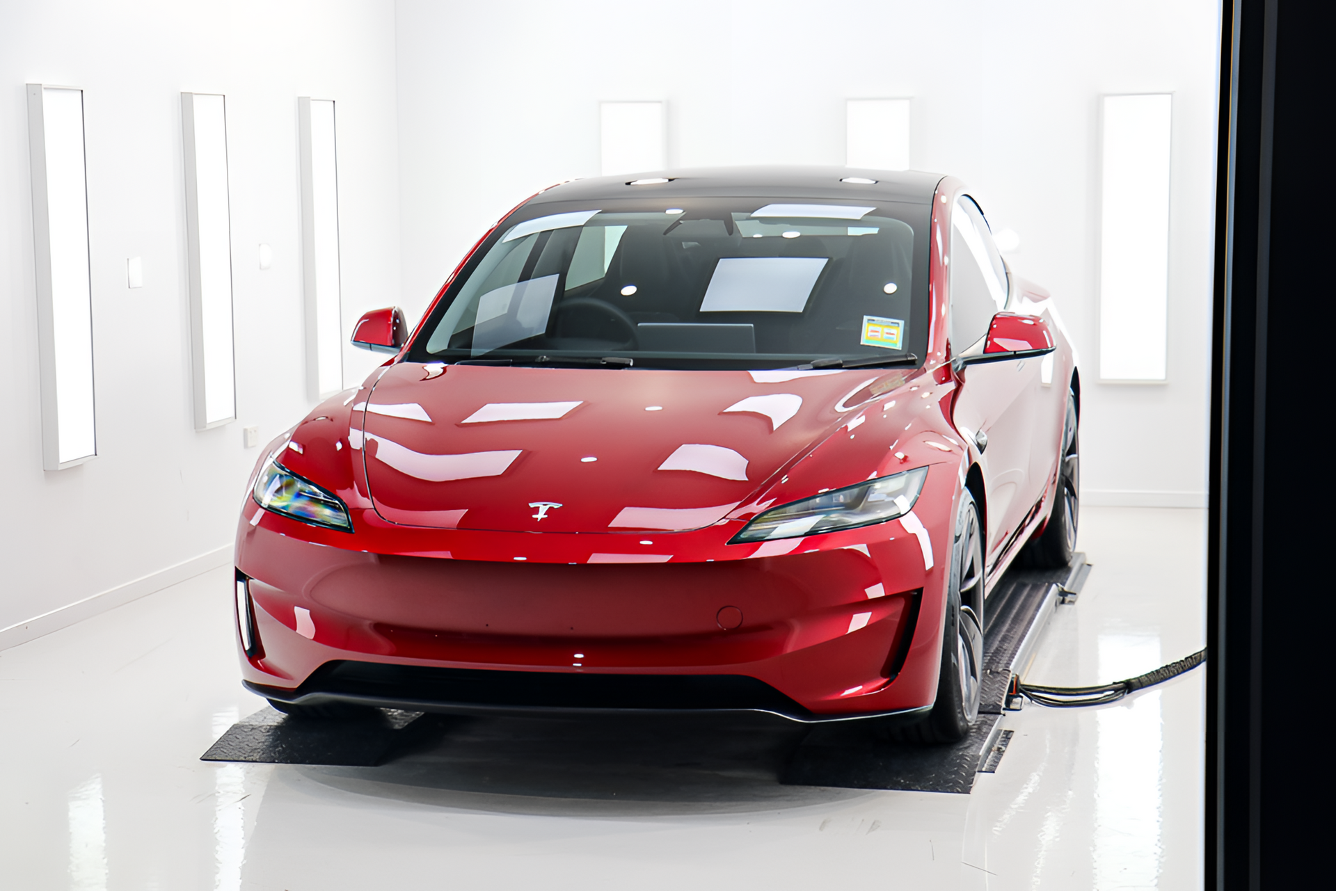 Black Audi RS6 Avant in a bright white garage with overhead lights.