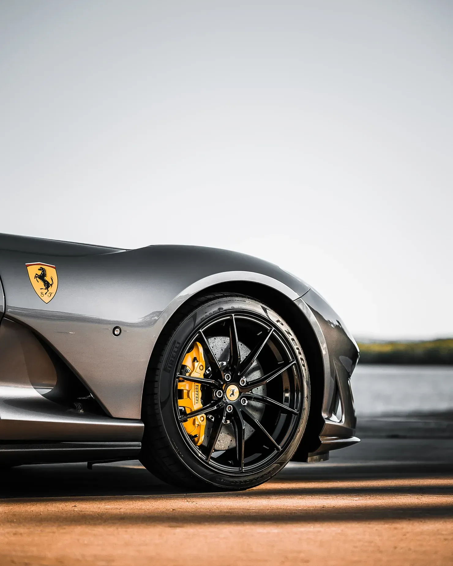 Gray Ferrari sports car with black rims and yellow brake calipers.