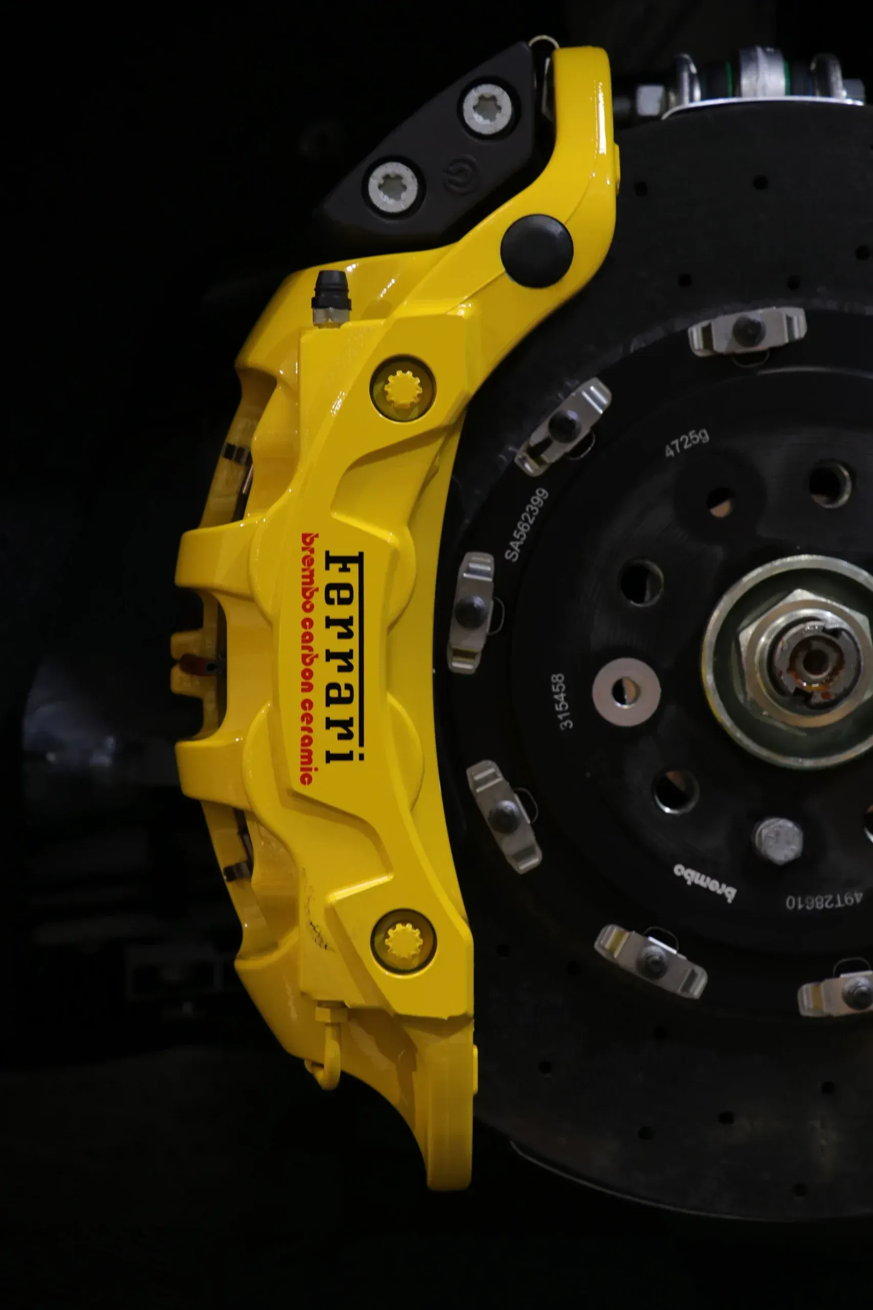 Yellow Ferrari brake caliper and rotor.