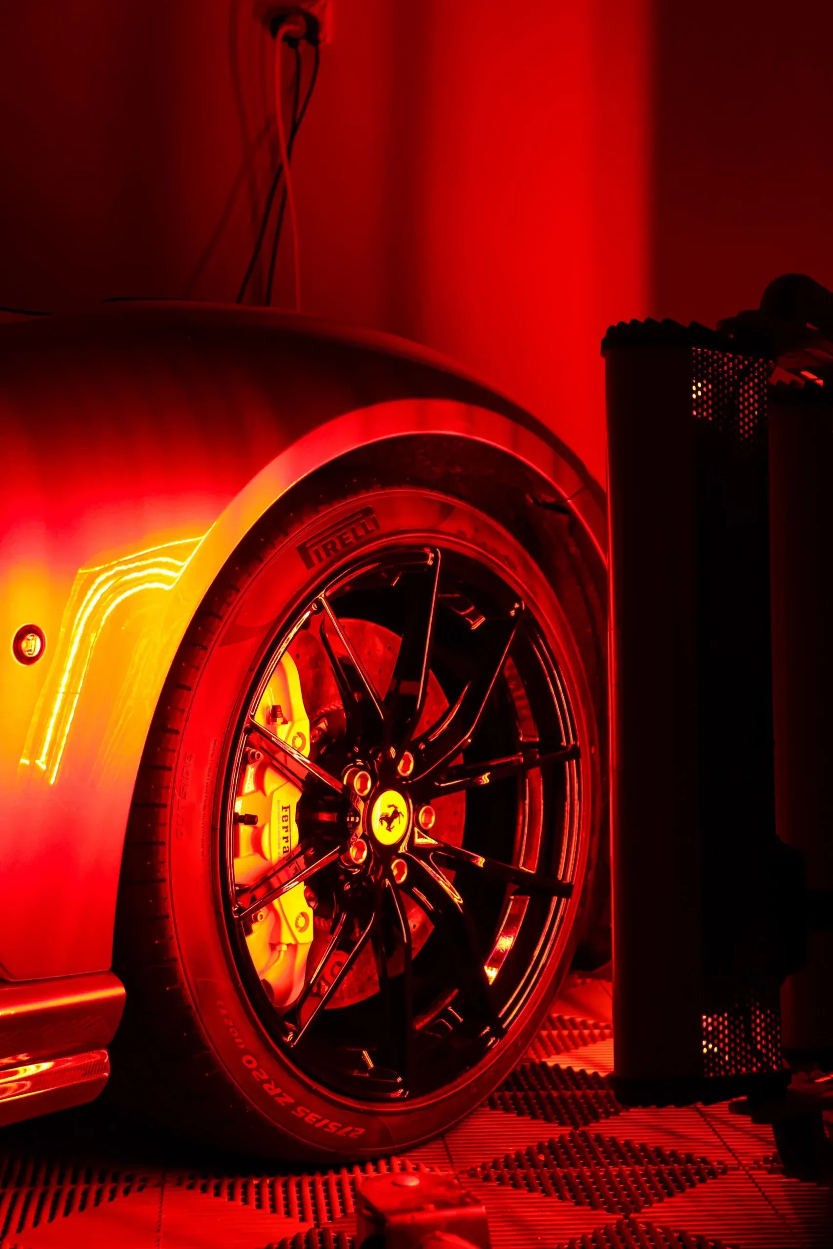 Red-lit close-up of a Ferrari sports car wheel and brake system.