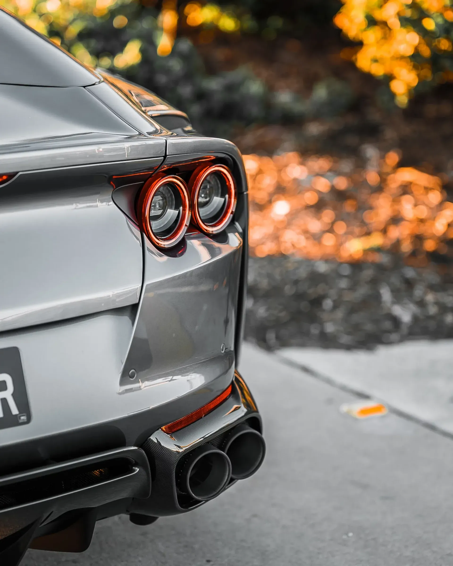 Rear view of a silver sports car with red taillights and dual exhaust.