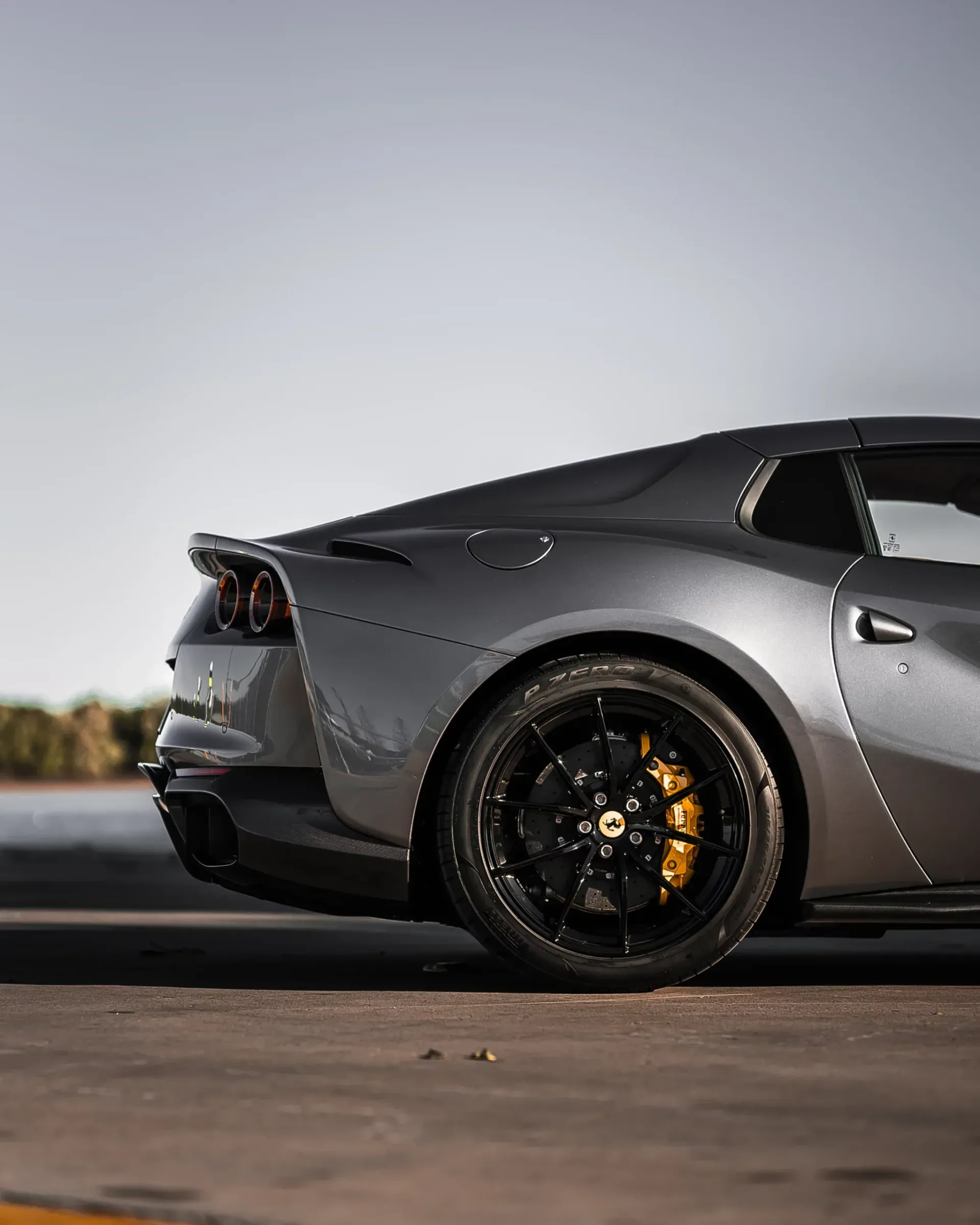 Gray Ferrari with black wheels and yellow brake calipers, parked outdoors.