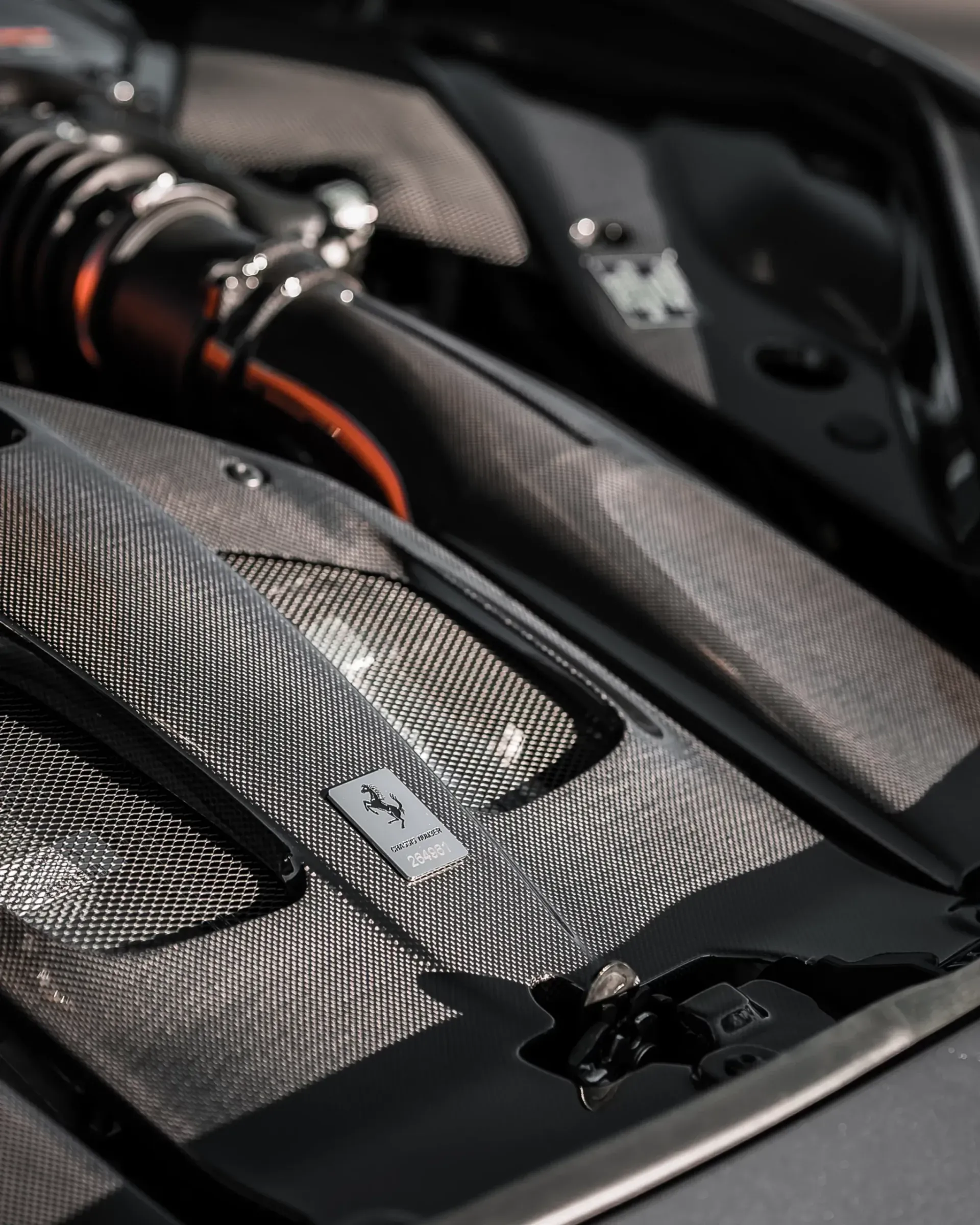 Carbon fiber car engine detail with silver accents.