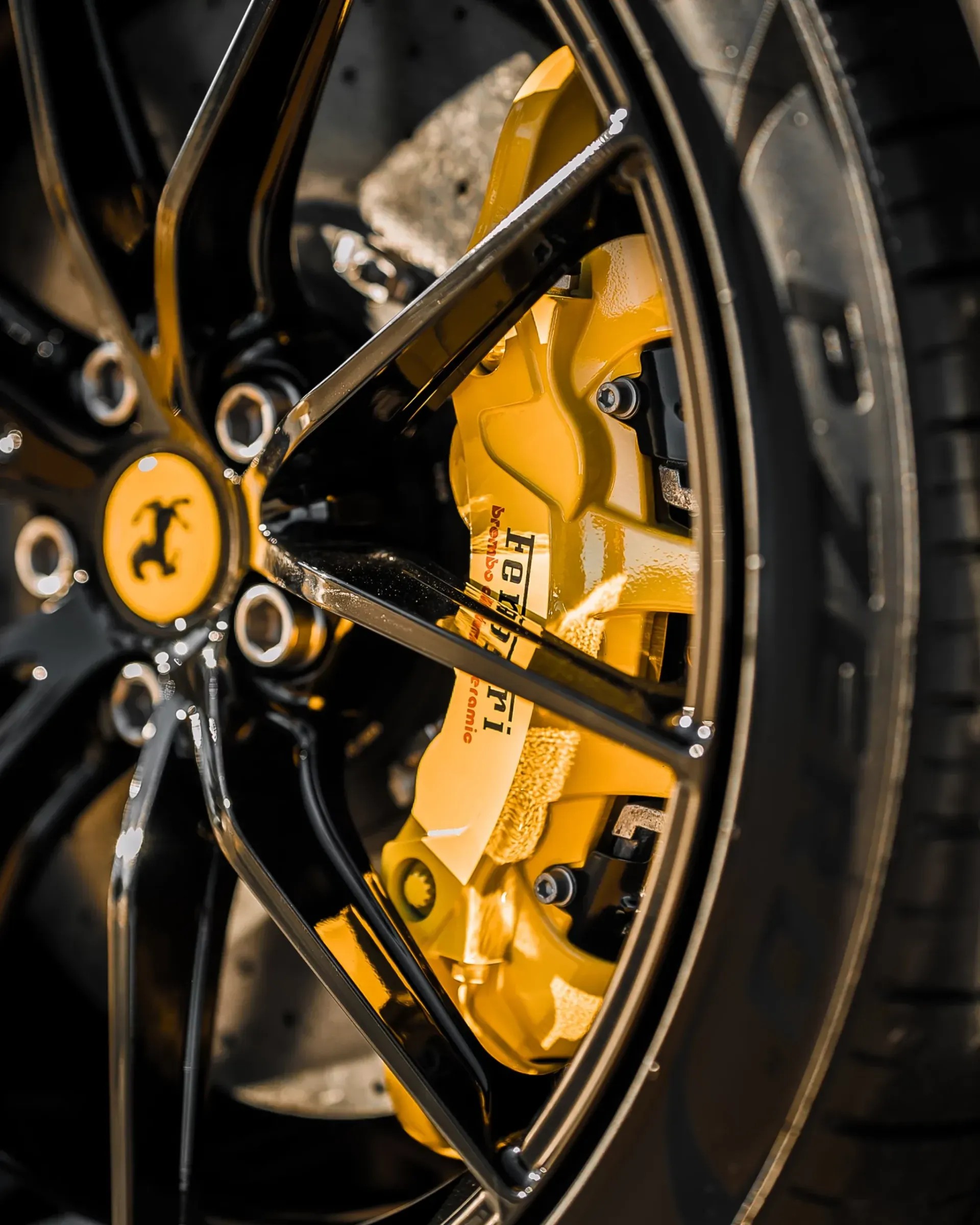 Black Ferrari wheel with yellow brake caliper.