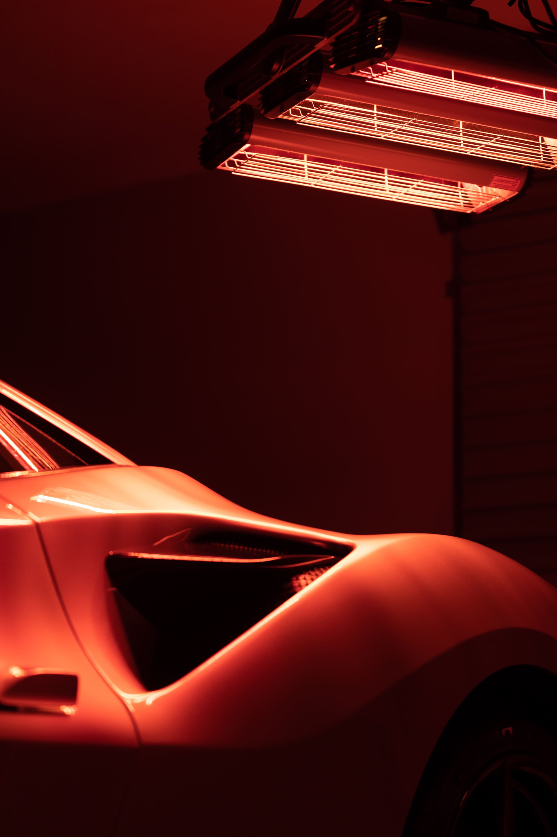 Man wearing black gloves applies liquid to a small part at a workbench in a workshop.
