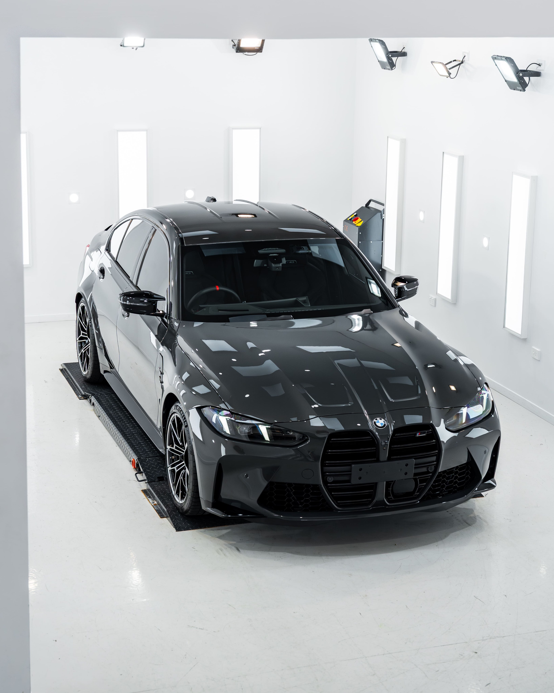 Silver sports car parked on a road, with greenery and a house in the background.