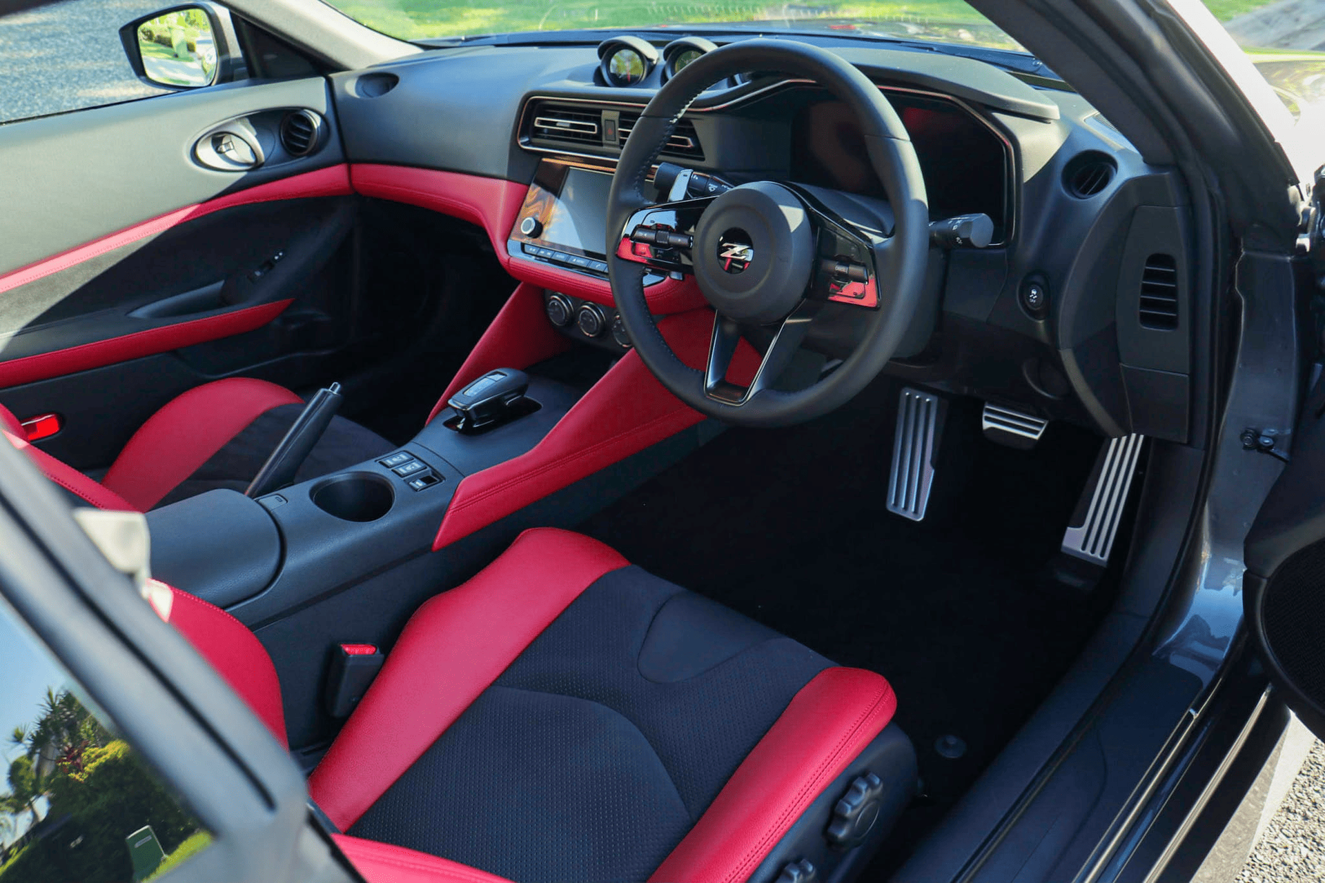 Interior view of a red and black sports car with a steering wheel and dashboard.