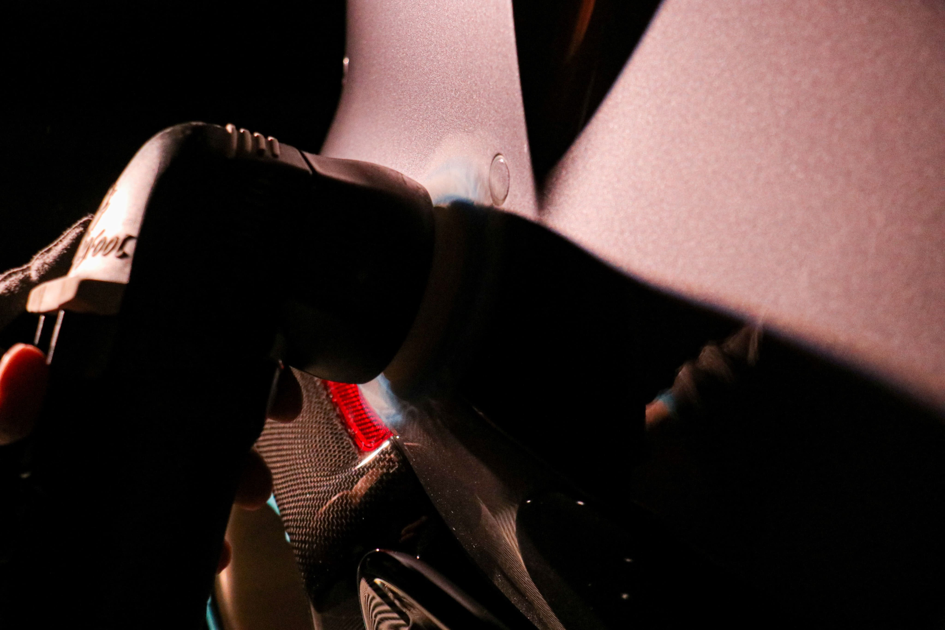 Person inspects a blue car door with a flashlight. Dark setting.