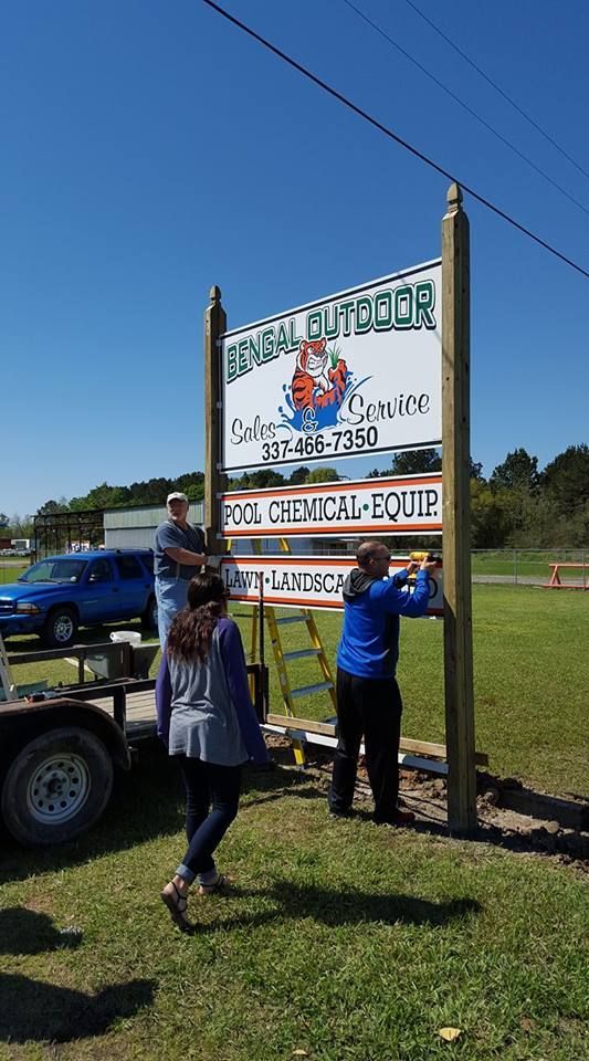 Three people installing a sign for 