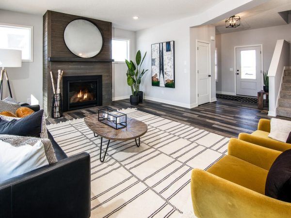 Living room with fireplace, rug, yellow armchairs, and art.
