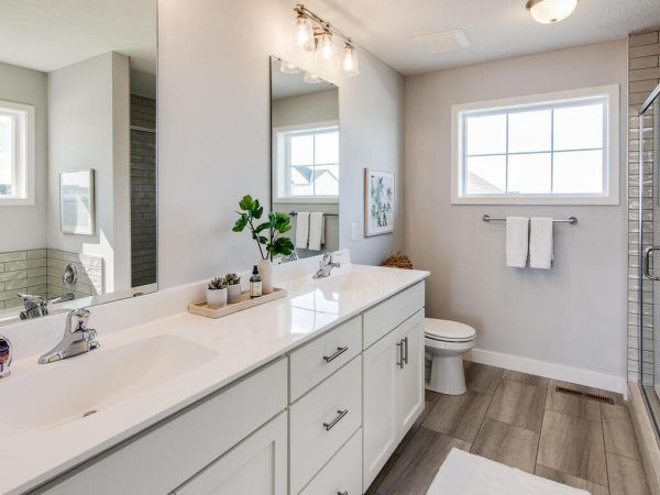 Modern bathroom with white vanity, double sinks, and light gray walls.