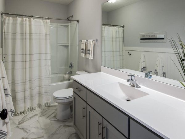 Bathroom with white and gray decor, including a shower, vanity, and toilet.