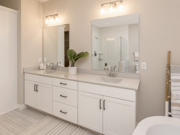 Modern bathroom with double vanity, white cabinets, and neutral walls.