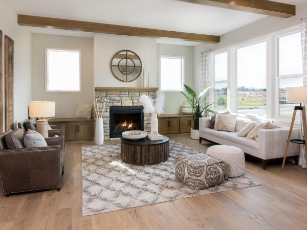 Living room with fireplace, neutral tones, light wood floors, large windows, and modern furniture.