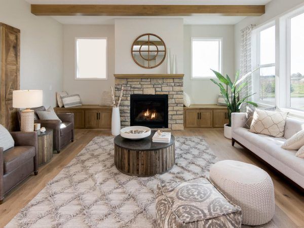 Living room with fireplace, light wood floors, neutral tones, and a large patterned rug.