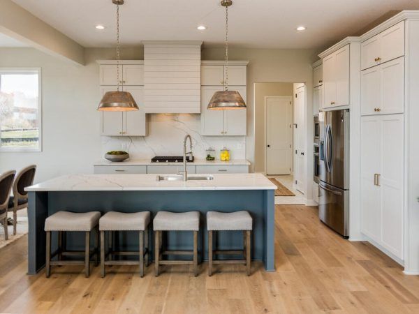 Modern kitchen with blue island, white cabinets, stainless steel appliances, and wood floors.
