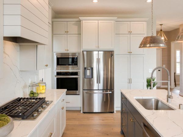 Modern kitchen with stainless steel appliances, white cabinets, and a marble countertop island.
