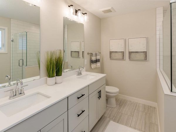 Modern bathroom with double sink vanity, shower, and toilet; neutral tones.