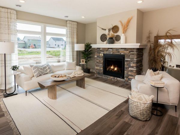 Living room with stone fireplace, cream sofa, and neutral decor, in a new home.