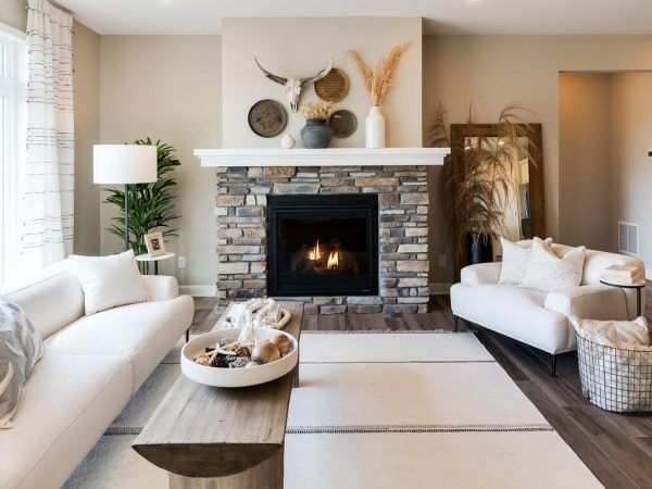 Cozy living room with fireplace, white sofas, and wooden coffee table. Neutral color scheme with rustic decor.
