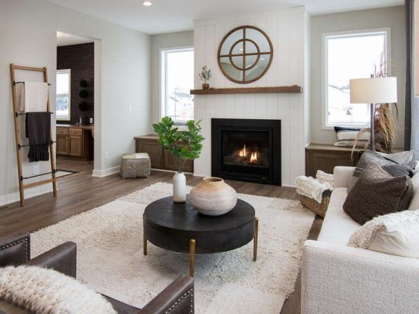 Living room with fireplace, white walls, rug, brown furniture, and a round coffee table.