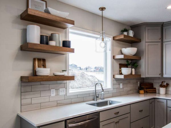 Kitchen with gray cabinets, white countertop, open shelves with decor, and a window.