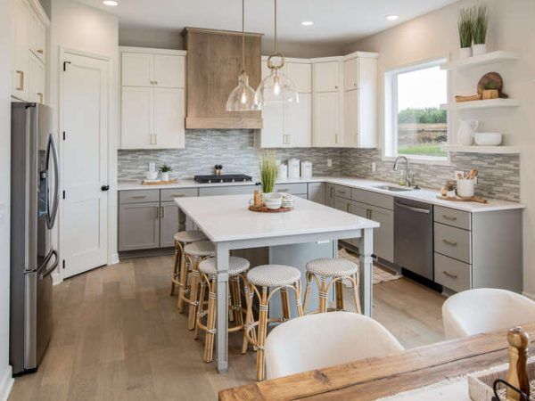 Kitchen with gray and white cabinets, island, and light wood floors.