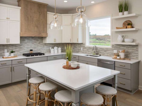 Modern kitchen with island and stools, white countertops, gray cabinets, and wood accents.