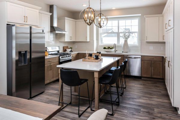 Modern kitchen with white and wood cabinets, stainless steel appliances, and an island with seating.