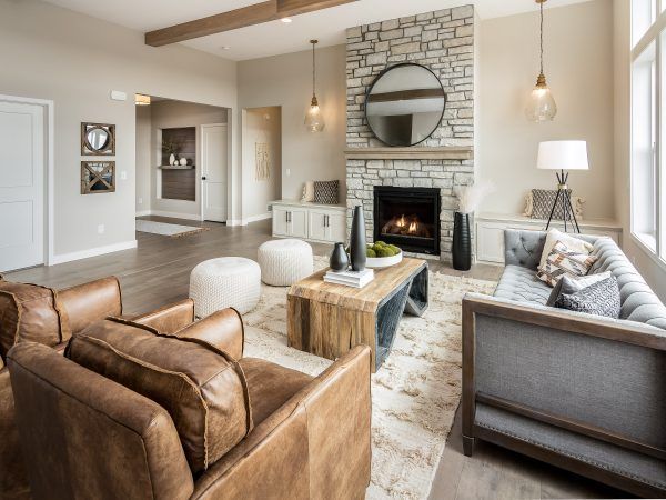 Living room with stone fireplace, leather chairs, gray sofa, and light wood floors.