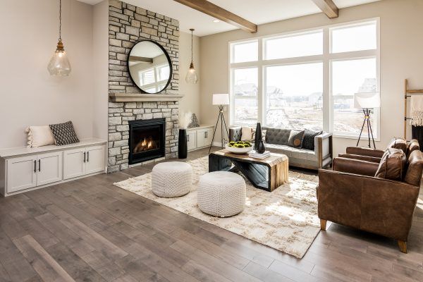 Living room with fireplace, stone wall, round mirror, neutral colors, leather and fabric furniture.