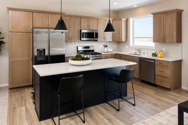 Modern kitchen with a black island and light wood cabinets.