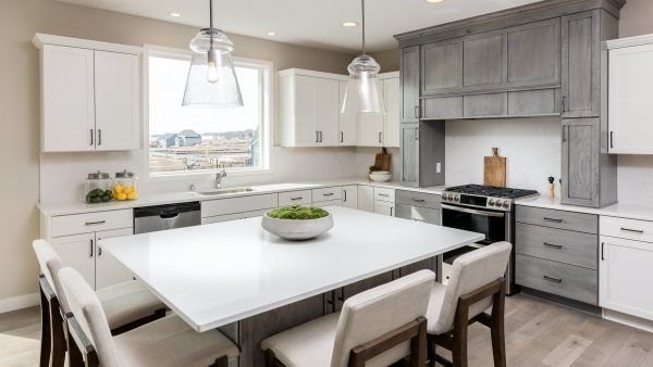 Modern kitchen with white and gray cabinets, large island, and hanging lights.