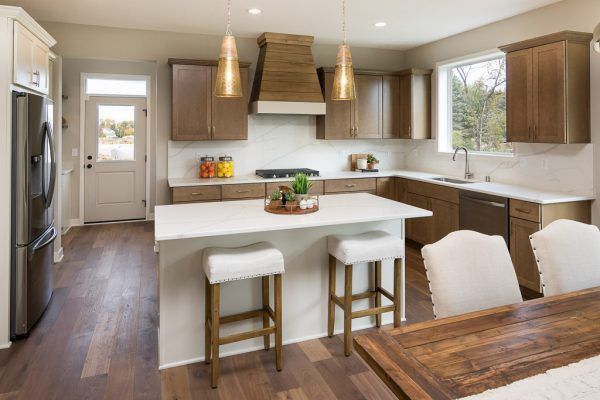 Modern kitchen with wood cabinets, white island, and pendant lights.