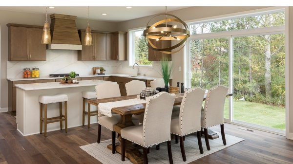 Kitchen and dining area with neutral tones, white countertops, and large windows overlooking a green landscape.