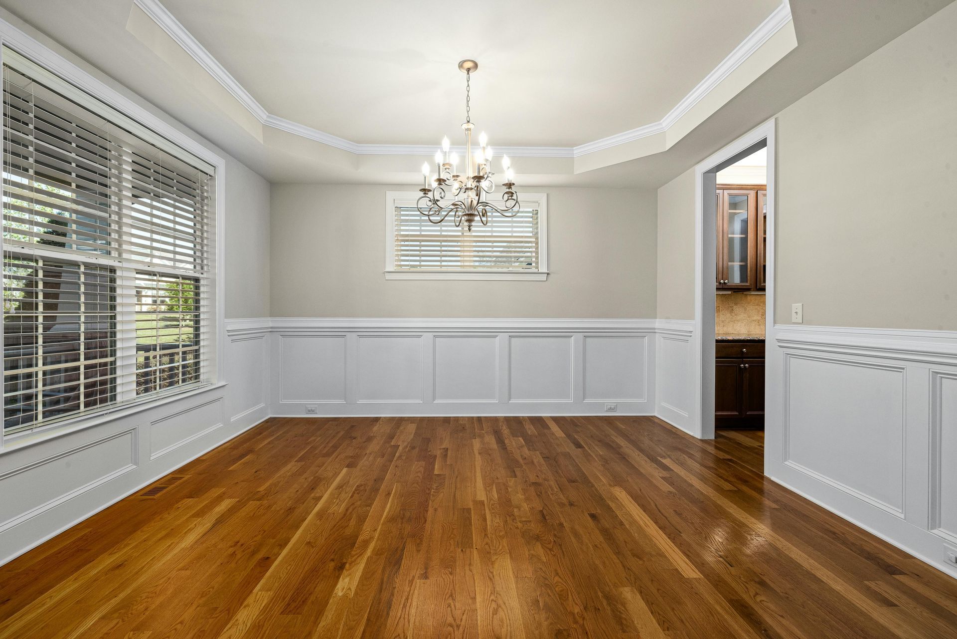Empty dining room with wood floors, chandelier, and white trim.