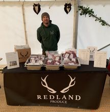 Redland produce logo and image of man in field with pheasants over shoulder