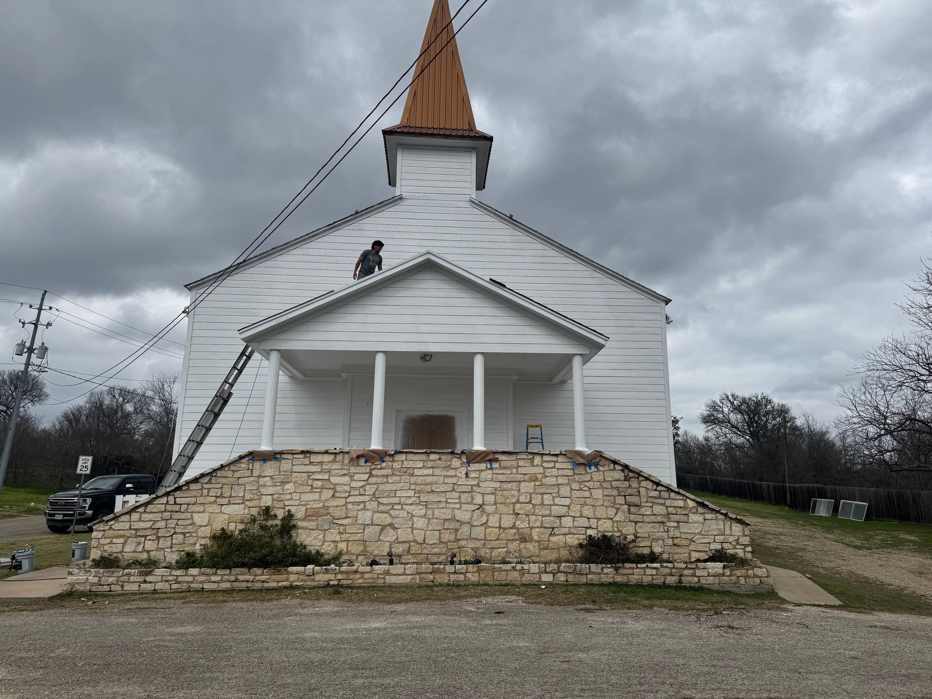 White church building with stone steps under a cloudy sky.